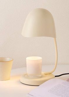 a white lamp sitting on top of a table next to a cup and saucer