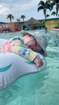 a baby is laying on an inflatable mattress and wearing a hat while swimming