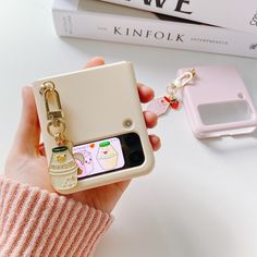 a person holding a cell phone case with a keychain attached to it