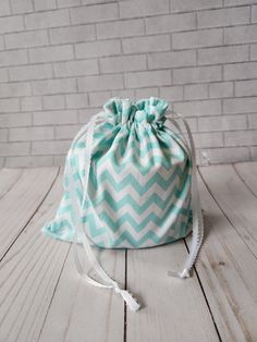 a drawsack bag sitting on top of a white wooden floor next to a brick wall