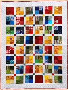 a quilt made with many different colors and patterns on the front, along with an orange border