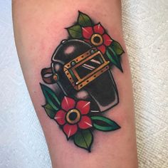 a tattoo on the leg of a person with a black hat and flowers around it