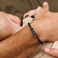 Introducing our exquisite custom black onyx beaded bracelet for men, set with stylishly crafted, beaded letters. This one-of-a-kind accessory showcases the perfect blend of sophistication and personalized style. Handcrafted with meticulous attention to detail, each black onyx bead is carefully selected to achieve a harmonious balance. The addition of the beaded letters adds a unique touch, allowing you to customize the bracelet with initials, meaningful words, or any desired combination. Perfect Personalized Black Beaded Bracelets As Gift, Personalized Black Beaded Bracelet As Gift, Personalized Black Beaded Bracelets For Gift, Black Beaded Wristband As Gift, Custom Name Black Stretch Bracelet As Gift, Black Name Bracelet With Round Beads As Gift, Personalized Black Wristband With Round Beads, Personalized Black Bracelets With Round Beads, Black Round Beads Name Bracelet Gift