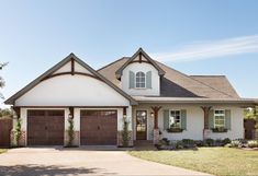 a white house with brown garage doors and windows