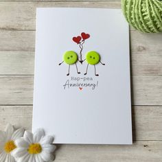 a card with two green buttons on it next to a ball of yarn and a flower