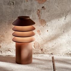 a light that is sitting on the ground near a wall and cement flooring area