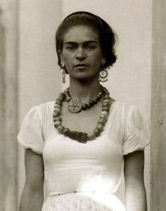 an old black and white photo of a woman in a dress with beads on her neck