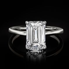 an emerald cut diamond ring on a black background