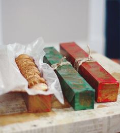 some food that is sitting on top of a wooden cutting board and wrapped in paper