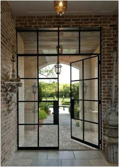 an open glass door leading into a courtyard with stone pillars and statues on either side