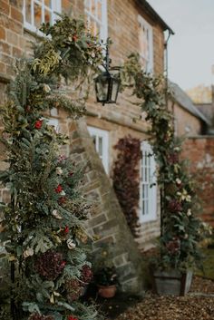 an outdoor area with potted plants and lights on the side of the building, surrounded by brick walls