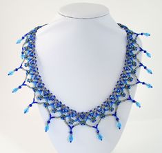 a white mannequin with a blue necklace on it's neck and beads