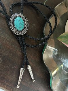 This awesome bolo tie has a southwestern design and genuine turquoise stone centerpiece. It is handmade in our shop.  The cord is genuine black leather. Our bolos pair nicely with many of our belt buckles! They make wonderful gifts.    The western bolo tie rope length is 39'' ; charm agate stone pendant size is 1 1 1/4'' x 1 1/2'' Vintage Black Jewelry For Western-themed Events, Black Concho Jewelry For Western-themed Events, Western Jewelry With Adjustable Length For Rodeo, Western Black Jewelry For Rodeo, Black Western Style Jewelry For Rodeo, Western Jewelry With Adjustable Length For Western-themed Events, Western Style Adjustable Jewelry For Western-themed Events, Concho Jewelry For Rodeo, Western Style Concho Jewelry For Gift