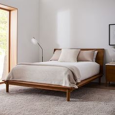 a bed sitting in a bedroom on top of a wooden floor next to a window