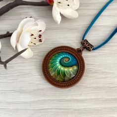 Turquoise blue wooden pendant necklace with fossil detail ammonite picture necklace. Cabochon jewellery, necklaces for women in the UK. This beautiful necklace is a round antique bronze tone  base which I've set with an emerald green ammonite fossil print glass cabochon,  it would make a perfect gift, maybe for a  birthday present. Its set on an 18 inch bright emerald green vegan suede cord, and fastens with a lobster clasp and extender chain. Gifts - If this item is a gift, please select 'gift Bronze Cabochon Necklace For Gifts, Handmade Turquoise Spiral Jewelry, Handmade Spiral Turquoise Jewelry, Bohemian Spiral Necklace For Gift, Bohemian Spiral Necklace As A Gift, Bohemian Spiral Necklace As Gift, Unique Blue Spiral-shaped Jewelry, Artistic Turquoise Necklace With Round Pendant, Unique Spiral Turquoise Jewelry