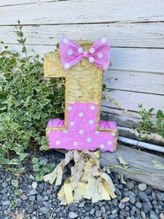 a pink and white number one sitting on top of a pile of rocks next to a bush