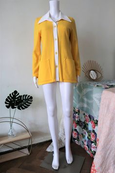 Preppy Swedish Vintage blazer/cardigan from the late 1960s or early 1970s. Made from a soft jersey fabric in yellow with white details, slightly fitted cut. Large contrasting collar, button tab and beautiful large button. Two front pockets, unlined. Looks great combined with a pair of flare jeans and clogs/mules. BRAND: Petri Swedish Design ERA: 1960s, 1970s COLOR: Yellow, white Fabric: Neospun jersey SIZE: Vintage size 38, fits best a modern size S - please check the measurements below for refe Vintage Spring Cardigan For Workwear, Retro Long Sleeve Cardigan For Work, Retro Yellow Cardigan For Spring, Yellow Retro Cardigan For Spring, White Fitted Retro Cardigan, Classic Yellow Long Sleeve Cardigan, Yellow Long Sleeve Cardigan For Work, Yellow Fitted Vintage Cardigan, Fitted Vintage Yellow Cardigan