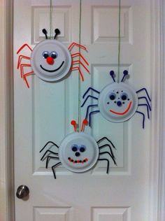 two paper plates with faces on them hanging from the side of a door decorated for halloween