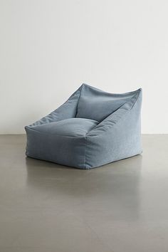 a blue bean bag chair sitting on top of a cement floor next to a white wall