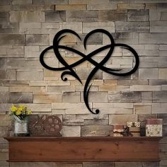 a heart shaped metal decoration on the wall above a fireplace with flowers in a vase