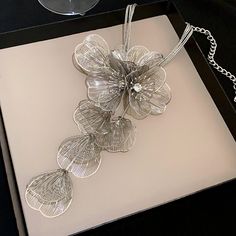 Silver Blossom Tassel: Pure Silver Floral Necklace Drawing inspiration from the splendor of nature, we present the "Silver Blossom Tassel" pure silver floral necklace. This artful piece captures the ephemeral beauty of a flower in bloom with the luster of sterling silver, where each petal is intricately textured, resembling delicate silver butterflies fluttering in the morning dew. Tales of Blossoms Throughout history, silver flowers have symbolized nobility. Our designers have infused this gran Silver Butterflies, Necklace Drawing, Sweet Jewelry, Banquet Party, Morning Dew, Elegant Necklace, Floral Necklace, Elegant Necklaces, Silver Flowers