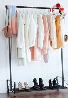 a rack with shoes and clothes hanging on it's sides in front of a white wall