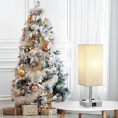 a white christmas tree with gold and silver ornaments in the corner of a living room