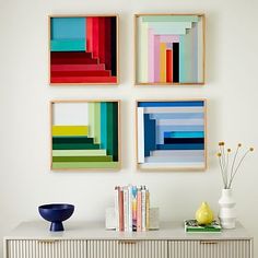 three colorful paintings hanging on the wall above a dresser