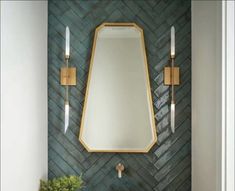 a bathroom sink with a mirror and two lights on the wall above it, along with a potted plant