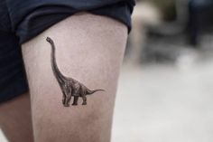 a small dinosaur tattoo on the thigh