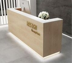 a wooden reception desk with flowers on top and the word design written in gold lettering