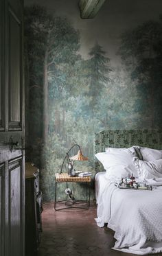 a bed sitting in a bedroom next to a forest wallpaper