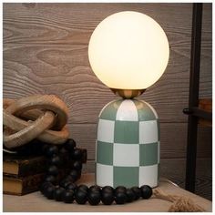 a green and white lamp sitting on top of a table next to some black beads