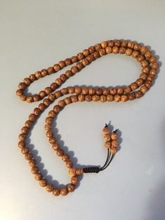 "Bodhi seed mala necklace made of 108 12mm beads with a Bodhi seed guru bead and an adjustable knot that allows you to change the length and tightness of the beads. Bodhi seeds are usually not polished so they are a solid color with small ridges or veins. Bodhi in Sanskrit translates to \"enlightened\" or \"awakened,\" therefore the Bodhi seed means \"enlightened seed.\" Bodhi is also a term in Buddhism to reflect a Buddha's understanding of the true nature of things. Many Buddhist wear the Bodh Spiritual Rosary With Round Beads For Meditation, Spiritual Rosary For Meditation With Round Beads, Spiritual Rosary With Large Beads, Holistic Wooden Beads Mala For Festivals, Adjustable Mala With 108 Beads For Rituals, Adjustable Spiritual Hand-strung Mala, Adjustable Hand-strung Spiritual Mala, Healing Mala With Round Beads For Festivals, Adjustable Brown Mala For Healing