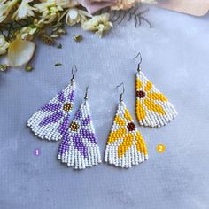 three pairs of beaded earrings with flowers in the background