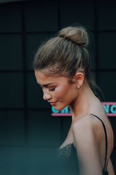 a woman with her hair in a high bun, wearing a black dress and earrings