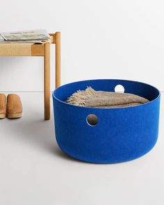 a large blue bowl sitting on top of a white floor next to a wooden table