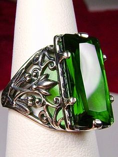 Green Emerald Ring Baguette Design#32 Introducing the Baguette D32, a stunning piece of wearable art that pays homage to the opulent Victorian era. Crafted with meticulous attention to detail, this exquisite filigree Antique reproduction in sterling silver is sure to captivate anyone with a love for vintage-inspired jewelry. At its center, lies a flawless 7ct green emerald gemstone, radiating a dazzling hue that catches the light with every movement. The baguette rectangle-cut gemstone measures Elegant Rectangular Jewelry For Evening, Elegant Engraved Emerald Jewelry, Green Oval Jewelry For Evening, Antique Green Jewelry For Evening, Classic Emerald Jewelry For Evening, Elegant Intaglio Ring Jewelry, Elegant Green Intaglio Ring, Classic Evening Emerald Jewelry, Elegant Green Engraved Jewelry