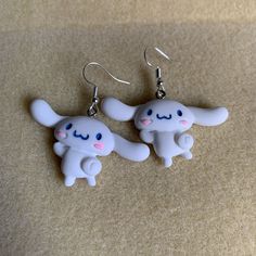 two little white elephants are hanging from earrings