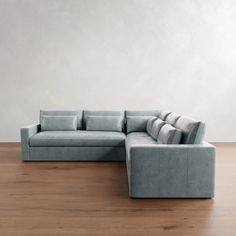 a large gray couch sitting on top of a wooden floor next to a white wall