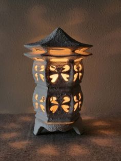 a lit up lantern sitting on top of a table next to a wall and floor