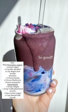 a person holding up a drink with purple liquid and ice cream on it, in front of a white background