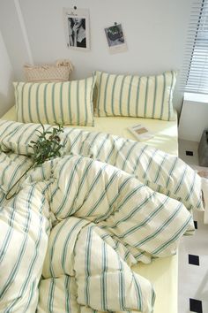 an unmade bed with green and white striped sheets