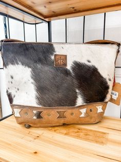 The Roswell Cowhide Tully Purse resembles our best-selling classic hair-on-hide cowhide collection, but is accented with unique aztec cut-outs in the genuine full grain veg tan leather. Finished with oils and wax for a slightly snuffed natural feel. Features Genuine hair on hide Full grain leather accents Zip top closure Wide leather shoulder strap 1 interior zip pocket, 2 interior scrunch pockets 1 interior keychain clasp STS embossed leather patch Interior concealed carry 17" W X 11" H X 5.5" D Please note hair on hide is a natural product and will wear under normal conditions. Each product may vary slightly in shading, hair length and color making each item a unique product. This product comes in assorted colors only and specific color requests cannot be accommodated. Children Bottoms, Authentic Turquoise Jewelry, Classic Hair, Color Making, Veg Tan Leather, Leather Accents, Resort Collection, Hair Length, Boot Accessories