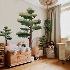 a child's bedroom with painted trees on the wall and wooden furniture in the foreground