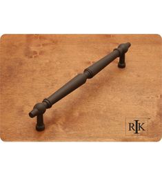 an old fashioned iron handle on a wooden surface with the word rk written below it