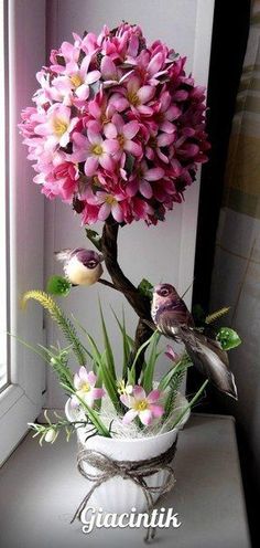 a vase filled with pink flowers sitting on top of a table next to a window