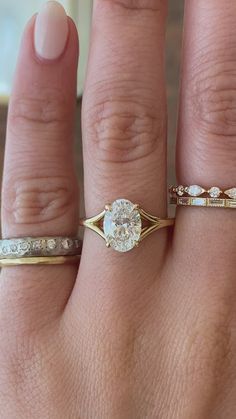 a woman's hand with three different rings on it and one has a diamond in the middle