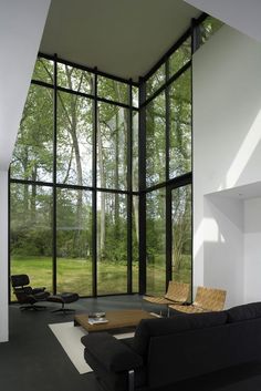 an empty living room with large windows and black furniture in front of the glass wall