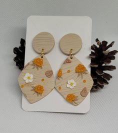 the wooden earrings are decorated with flowers and pineconi on them, along with a pine cone